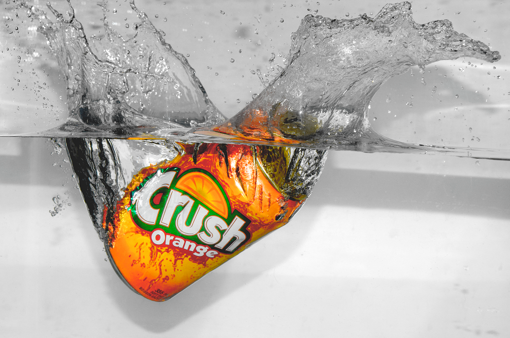 A can of soda being dropped into a basin of water